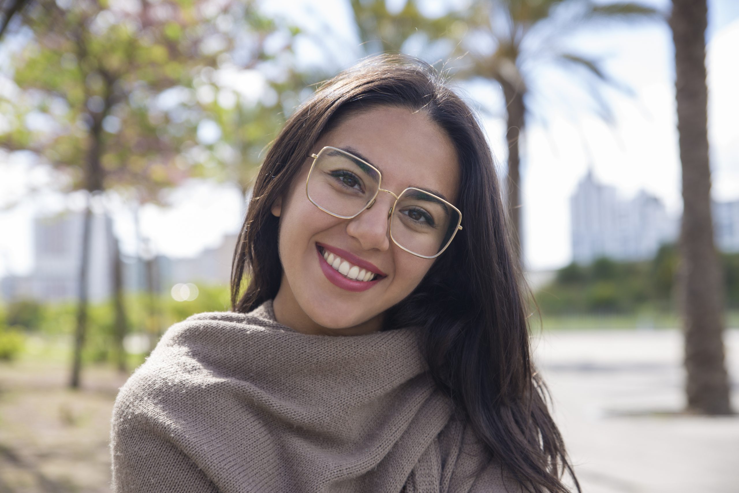 mujer bastante joven feliz que presenta en la camara en parque de la ciudad